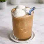 Banana Coffee Drinks served in a tall glass with a creamy iced coffee base topped with vanilla ice cream and a blue straw