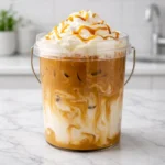 TikTok Coffee Bucket Recipe showing a creamy iced caramel coffee with milk swirls and whipped cream topping in a clear bucket-style cup